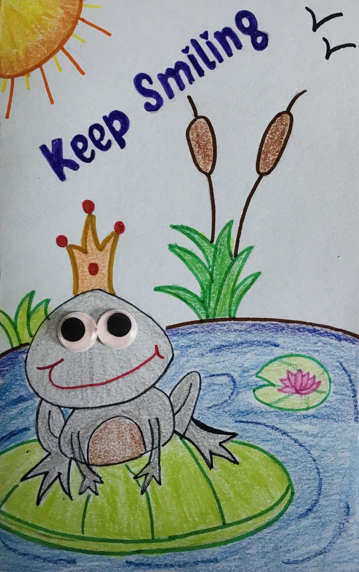 Drawing by Sumita Bose of a smilling frog with a crown on its head, staying on a leaf in the middle of a lake. Above is the sun and it is written Keep smiling.