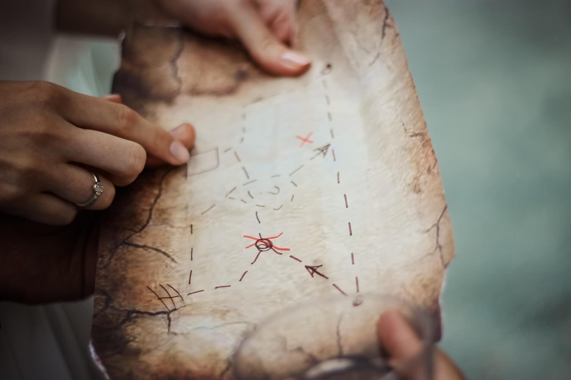 Photograph of a woman's hand. She points with her finger at a place on a drawn map. The map seems to display the attack strategy.