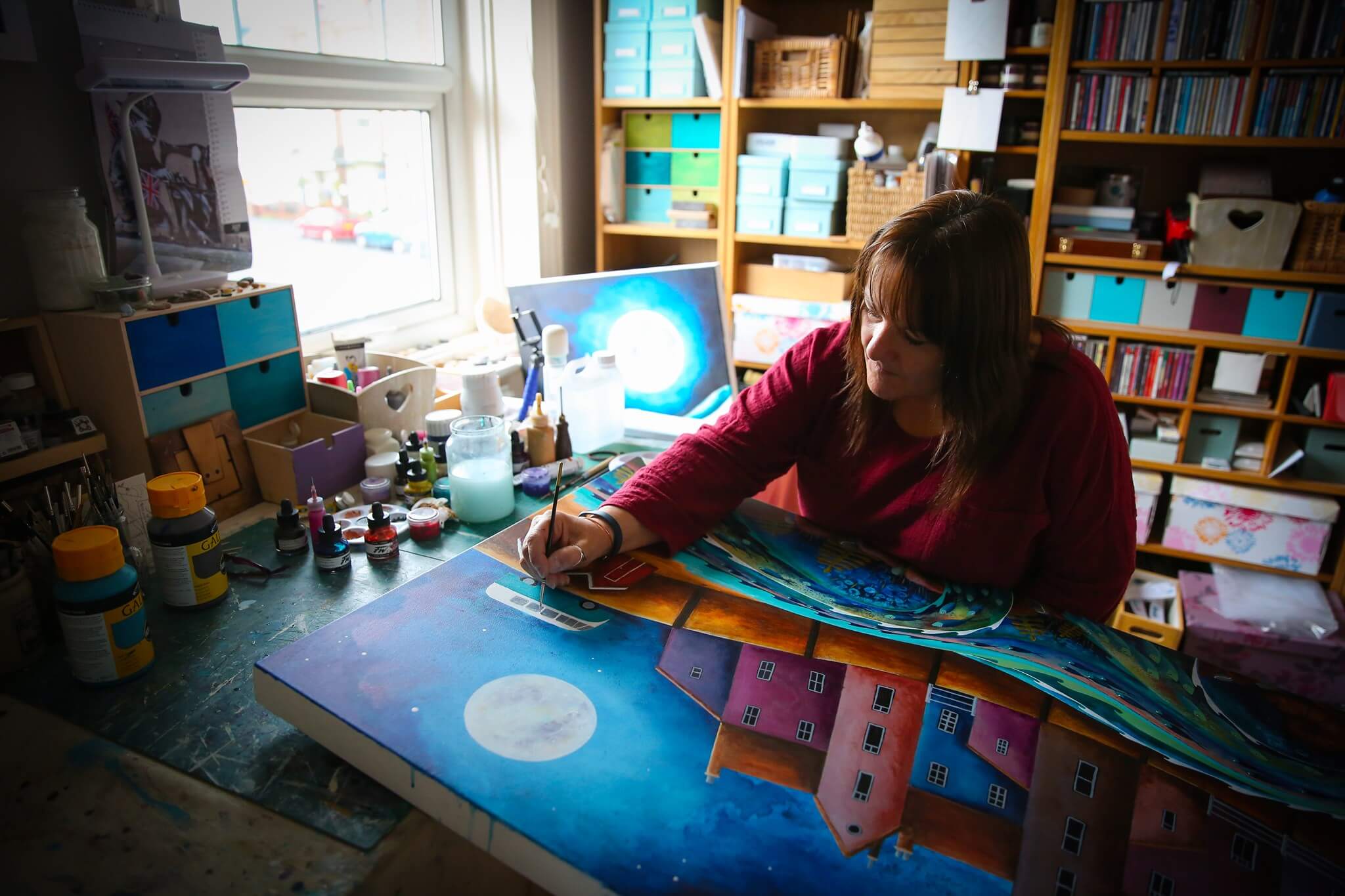 Photograph showing Briget Wilkinson working on one of her paintings in her studio in the UK.