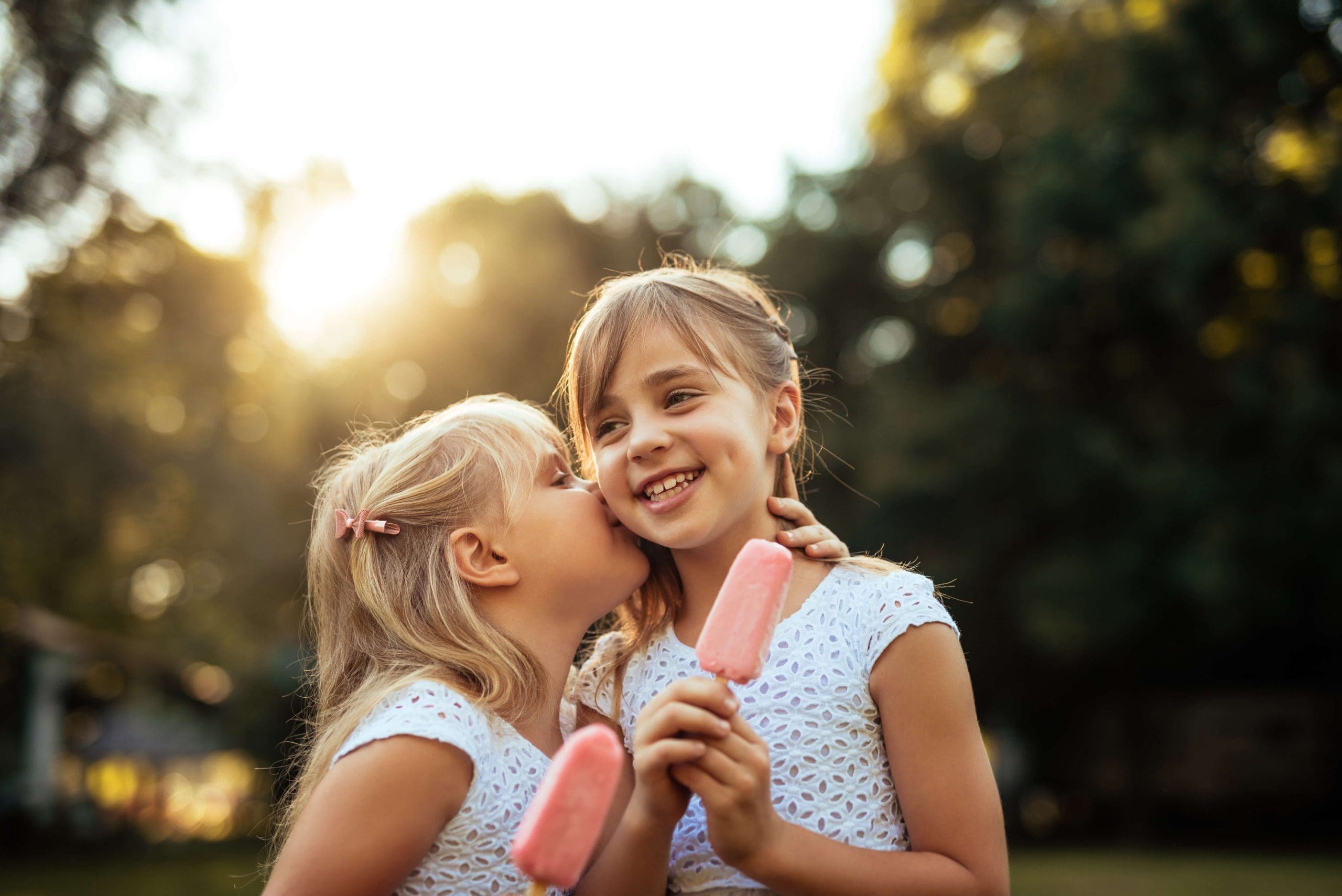 Photograph of two sisters hugging each other while they enjoy their ice cream.