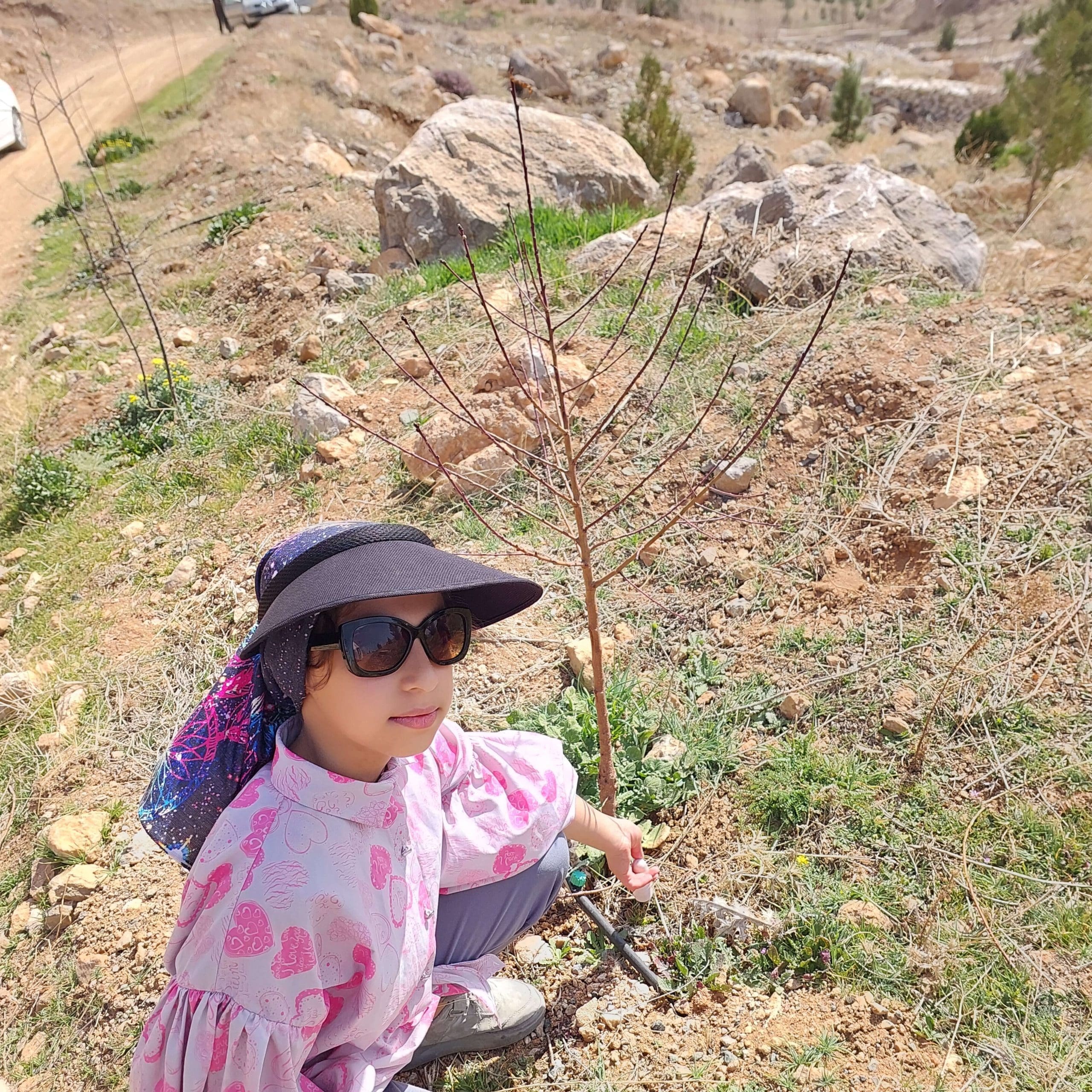 Photograph of the young ambassador for the environment, Baran Fateminejad, from Iran, age 9, planting a tree.