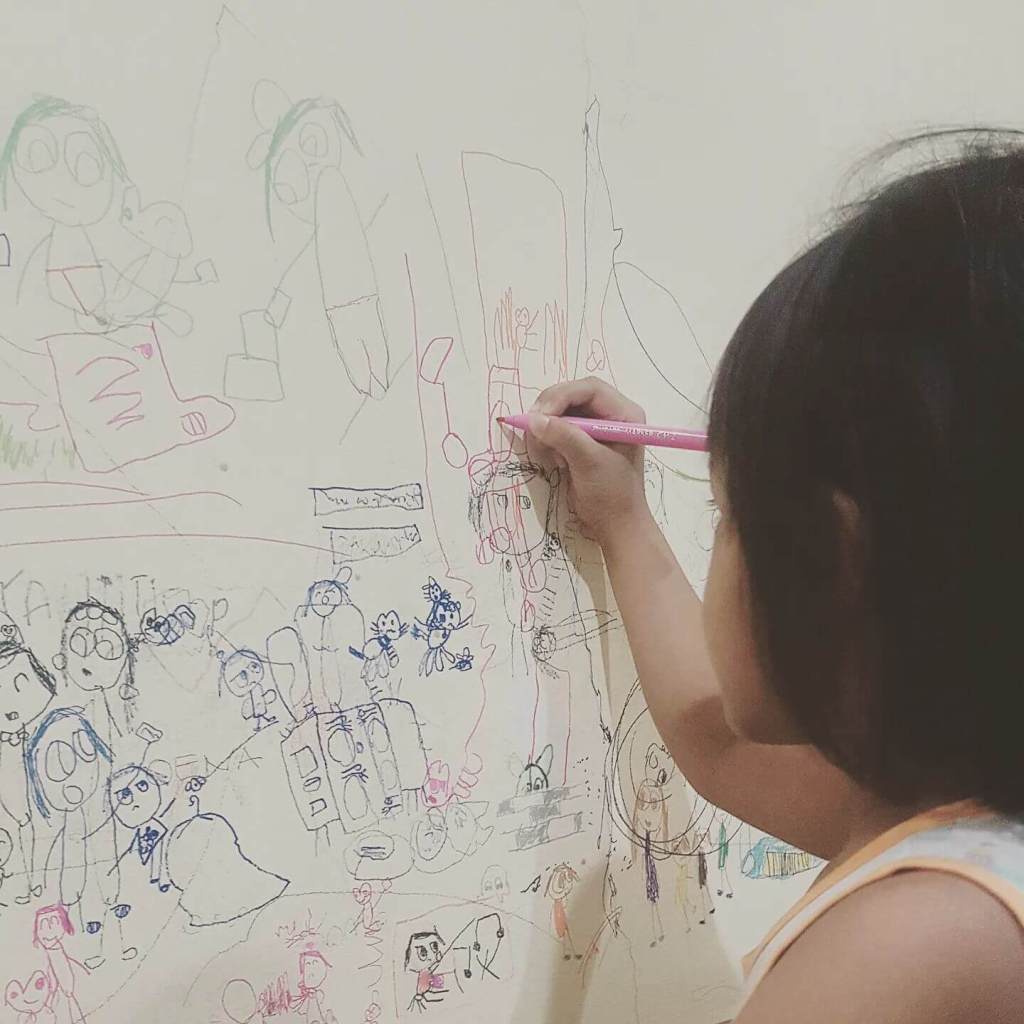 Young artist Dira Oena painting on a wall